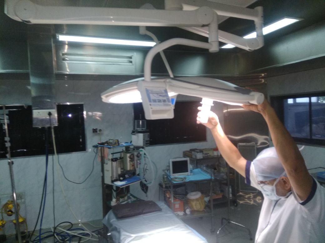 Clinician adjusting the 500 mm auxiliary dome of a dual-head LED surgical light during installation calibration in a Colombian hospital