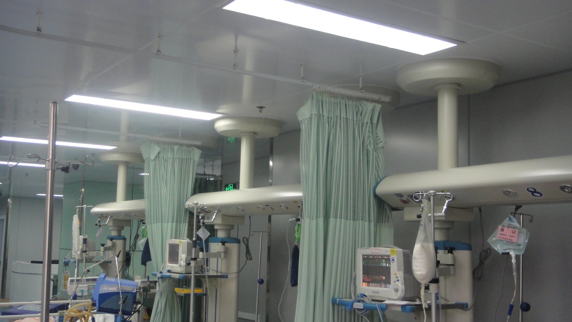 Multi-Bed ICU Ward with QF-JX-300 ICU Bridges Installed Across All Beds Multi-bed ICU ward at Shanghai Jing'an District Central Hospital showing multiple QF-JX-300 ICU bridges installed in parallel across the patient beds with infusion pumps, monitors and accessories mounted on each bridge