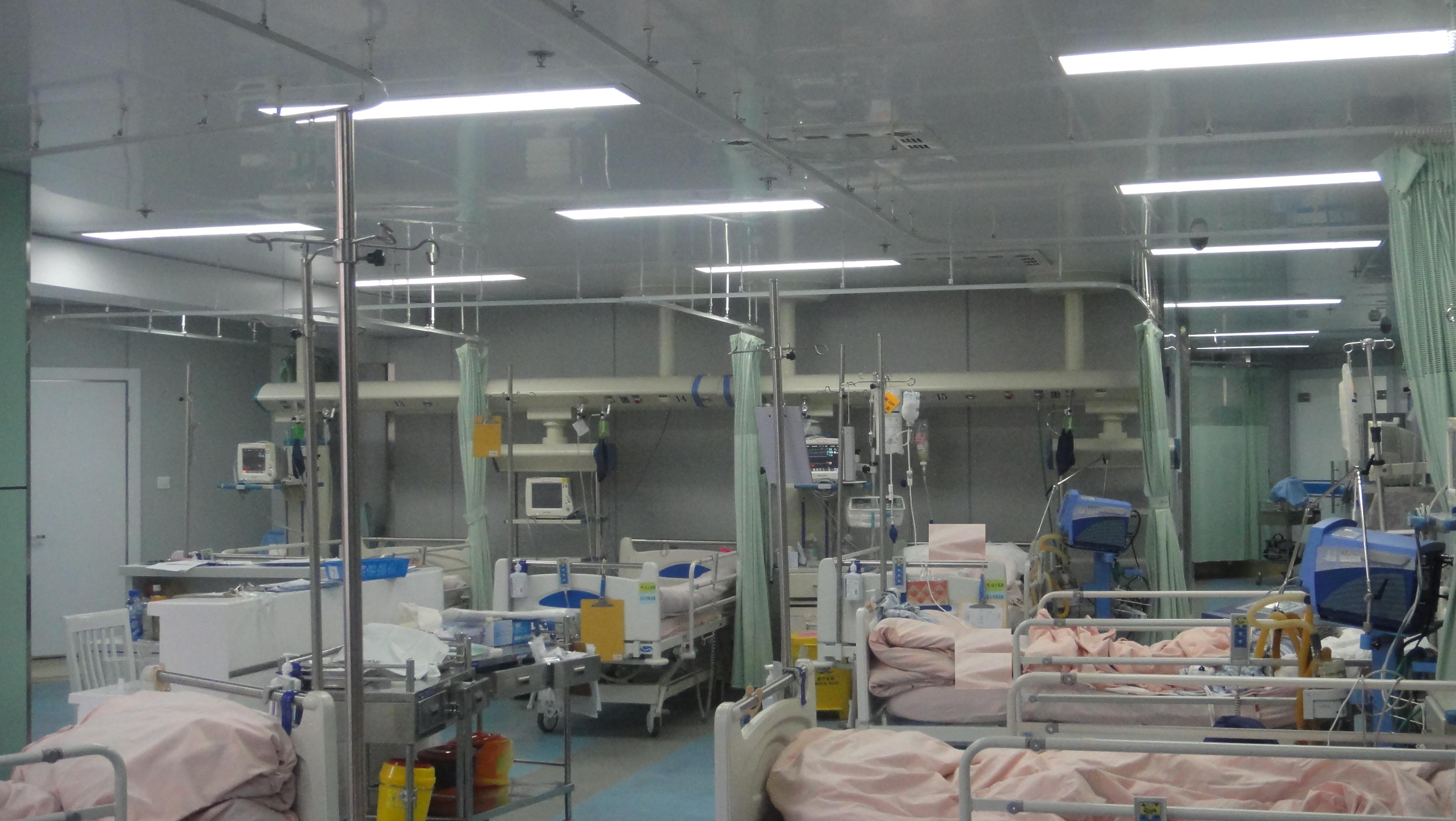 Wide-angle view of an ICU ward at Shanghai Jing'an District Central Hospital showing ceiling-mounted ICU bridges running along a row of patient beds equipped with ventilators, monitors, and infusion pumps