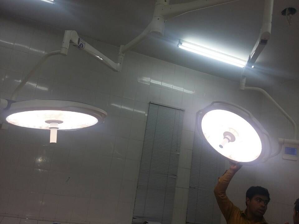 Pakistani military hospital technicians performing on-site installation and clinical commissioning of LEDD700/500 ceiling operating lights, verifying dual-dome cold-light LED illumination against the operating table surface