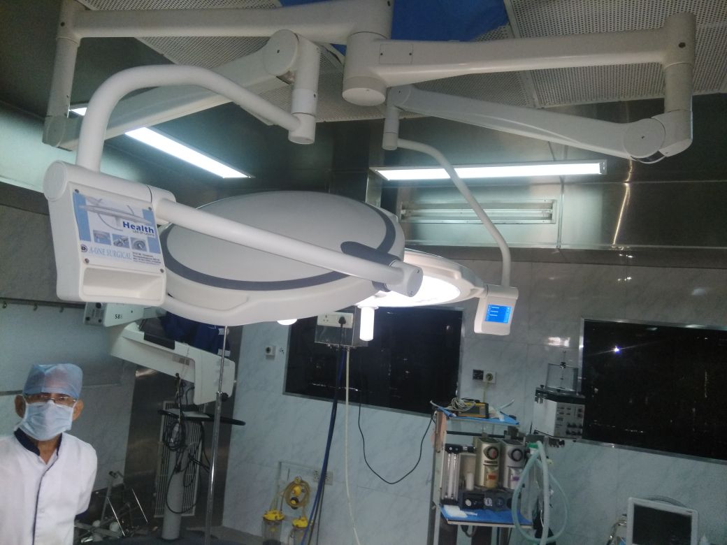 Colombian surgeon standing beside a newly installed dual-dome LED surgical light system in a modern hospital operating theater