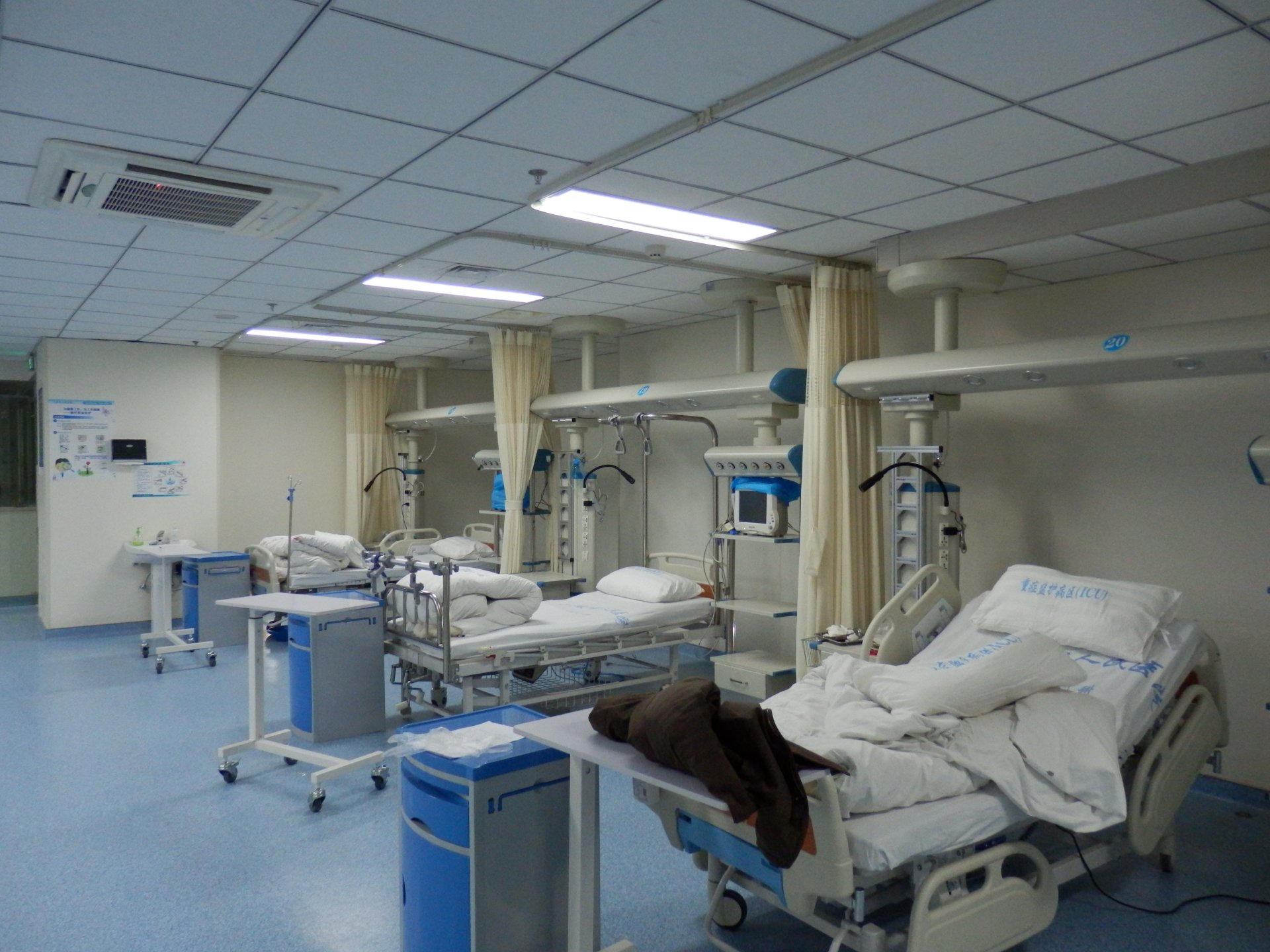 Ceiling-mounted ICU bridge system installed at Lu'an People's Hospital showing dry and wet zone separation between adjacent ICU beds with medical pendant columns