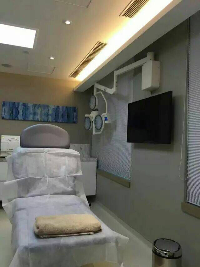 LEDB740 wall mounted LED surgical light installed in a Hong Kong day clinic procedure room with a low ceiling, supporting minor surgical and examination procedures