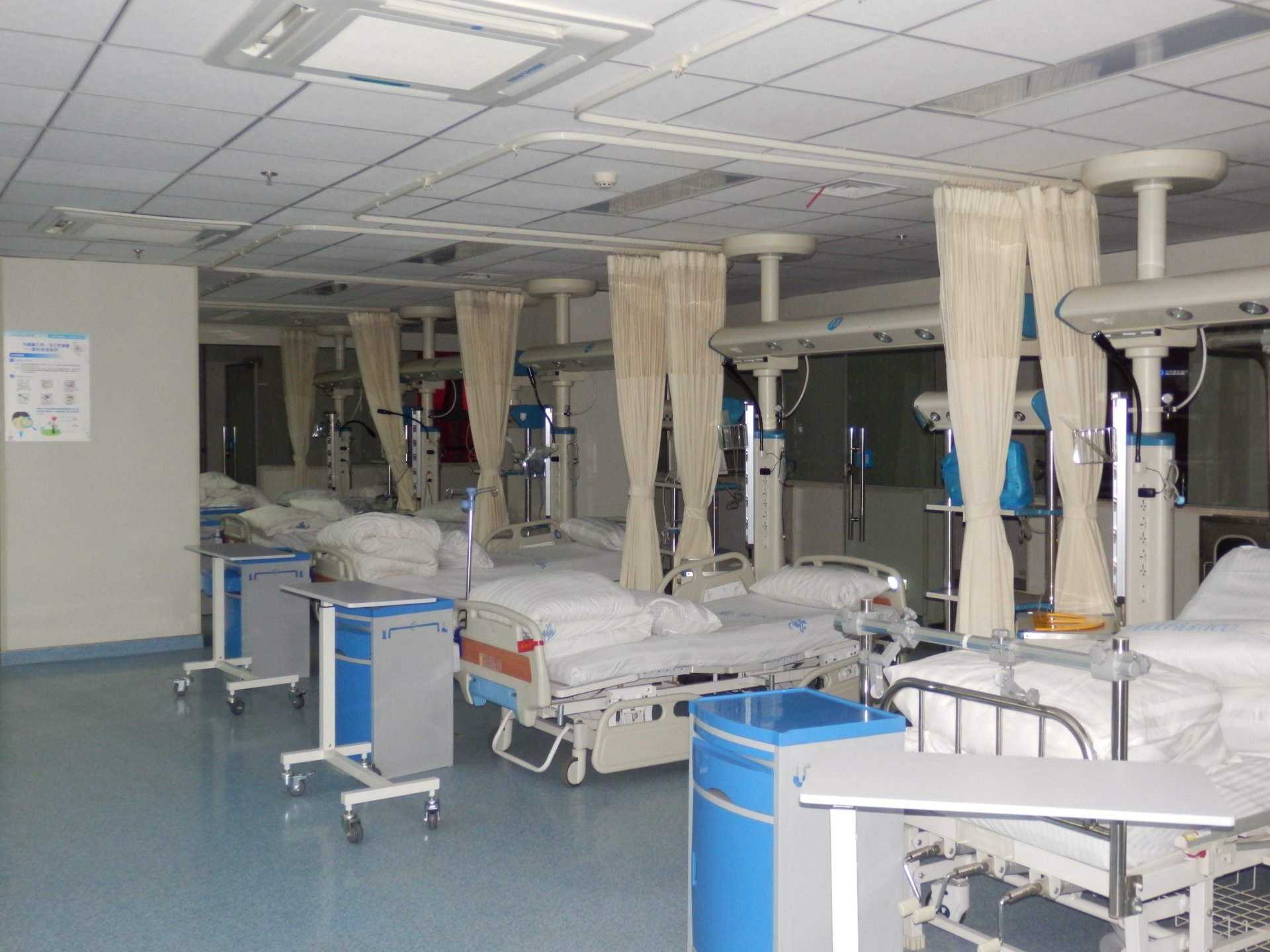 Newly commissioned QF-JX-300 ICU bridge spanning patient beds in the intensive care unit of Lu'an People's Hospital, integrating medical gas delivery, power, data and nurse-call connections above the head of bed