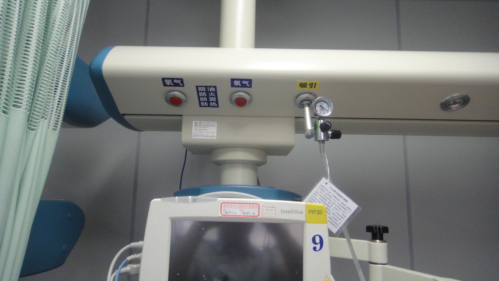 Close-up of Medical Gas and Power Terminals on the ICU Bridge Close-up of the ICU bridge dry and wet zones at Shanghai Jing'an District Central Hospital, showing labeled oxygen outlets, suction connector, electrical sockets and nurse-call socket integrated into a single overhead service bridge